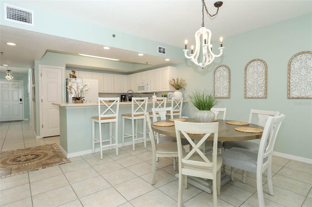 A dining area and kitchen with white cabinets, a round wooden table, and light-colored walls — 5300 S ATLANTIC AVE UNIT 9-304, NEW SMYRNA BEACH, FL