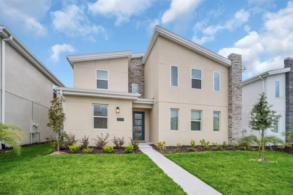 A two-story house with a beige stucco exterior, stone accents, and a front walkway — 2854 BOOKMARK DRIVE, KISSIMMEE, FL