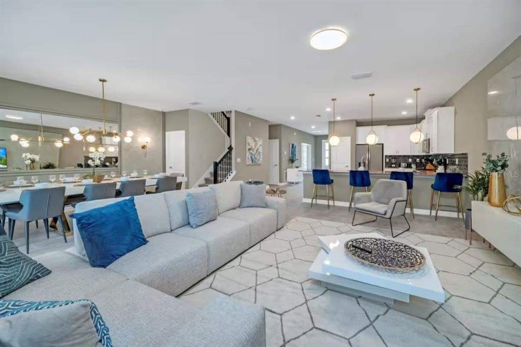 An open-concept living room features a large gray sectional, dining area, and kitchen with stools — 2854 BOOKMARK DRIVE, KISSIMMEE, FL