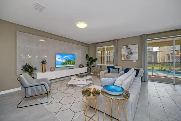 A modern living room features a large marble accent wall, gray sofa, and pool view — 2854 BOOKMARK DRIVE, KISSIMMEE, FL