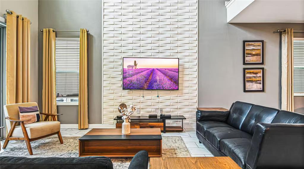 A living room features a textured white accent wall, a mounted television, and leather furniture — 2791 PUNCTUATION PLACE, KISSIMMEE, FL