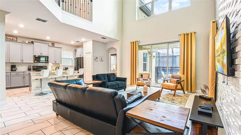An open-concept living room and kitchen with high ceilings, tile floors, and yellow curtains — 2791 PUNCTUATION PLACE, KISSIMMEE, FL
