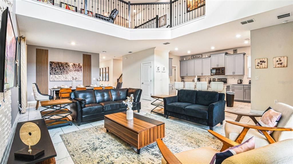 An open-concept living room and kitchen area features high ceilings, tile floors, and modern furniture — 2791 PUNCTUATION PLACE, KISSIMMEE, FL