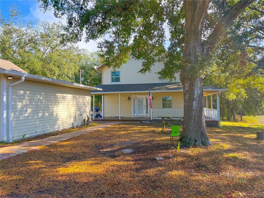 A two-story yellow house with a front porch, a large tree, and a brick walkway — 2827 SANCTUARY LANE, WINTER GARDEN, FL