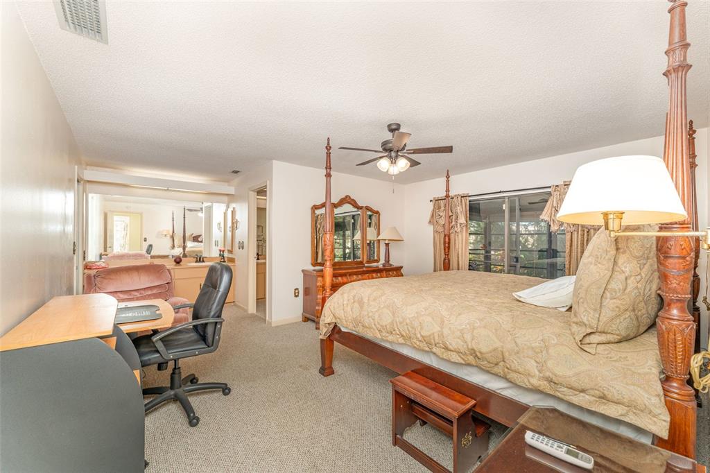 A bedroom features a four-poster bed, a desk, a dresser, and a ceiling fan — 4240 CREEKWOOD LANE, MULBERRY, FL