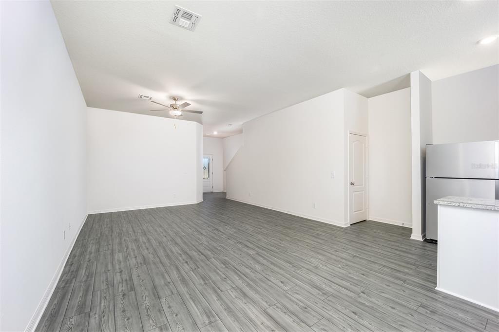 An open-concept living area features gray wood-look flooring, white walls, and a ceiling fan — 709 POPPY LANE, DUNDEE, FL