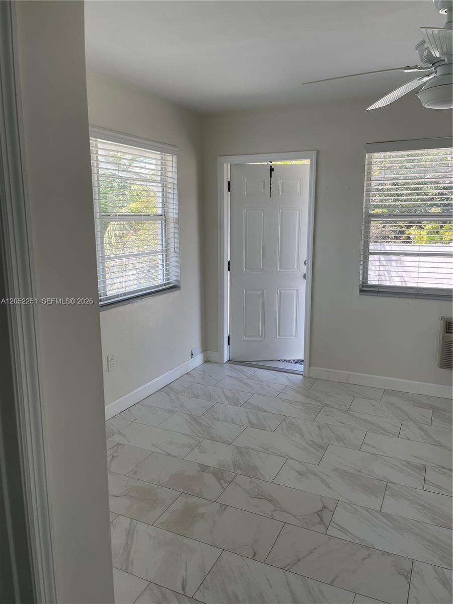 A room with white marble-look tile flooring, two windows with blinds, and an open door — 11890 NE 16th Ave # 6, Miami FL 33161, MIAMI, FL