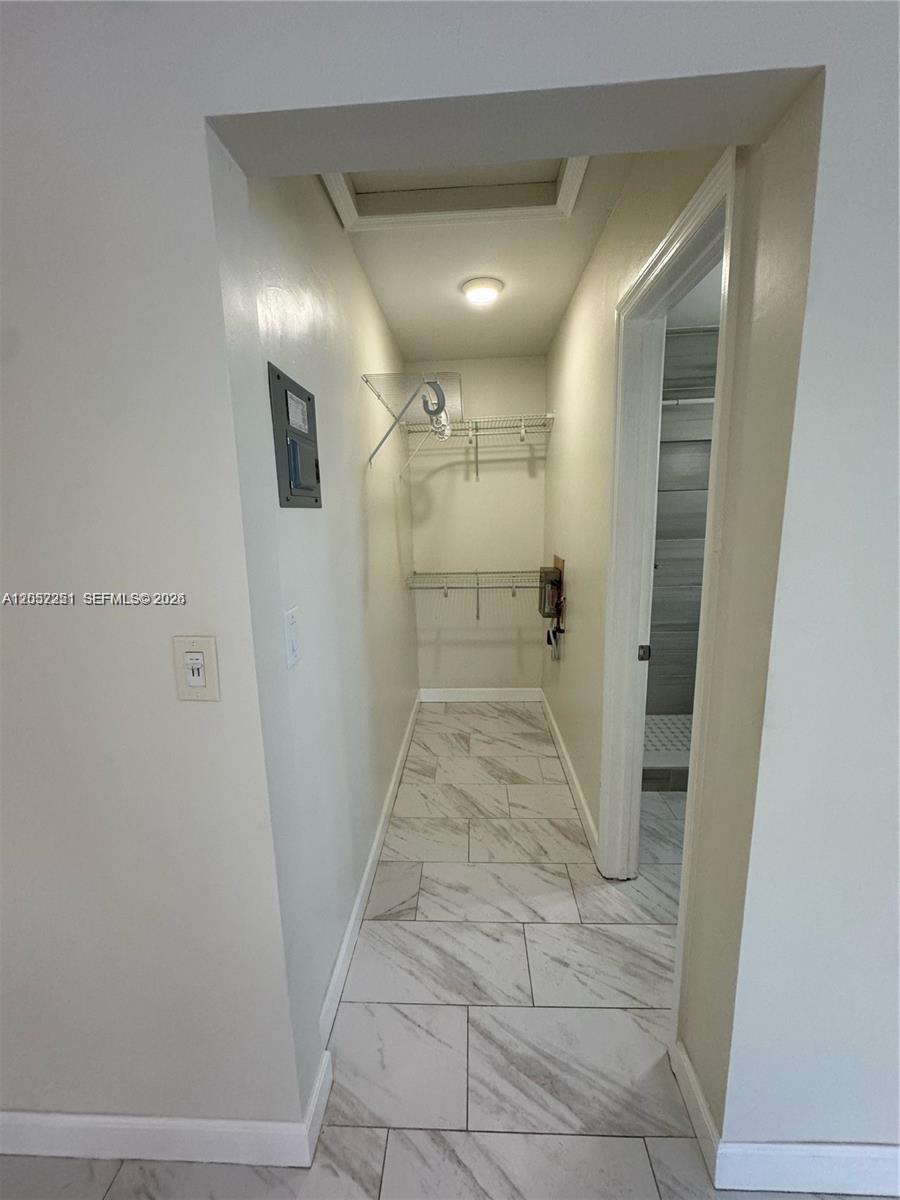 A narrow walk-in closet features white tile flooring, wire shelving, and a ceiling light — 11890 NE 16th Ave # 6, Miami FL 33161, MIAMI, FL