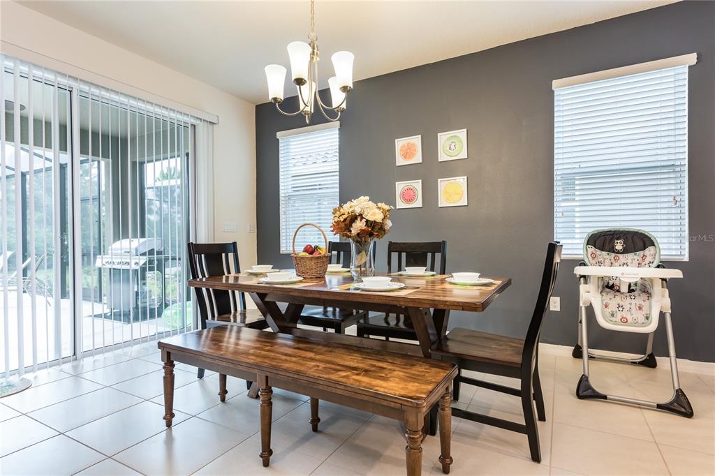 A dining room features a wooden table with a bench, chairs, and a high chair — 5231 WILDWOOD WAY, DAVENPORT, FL