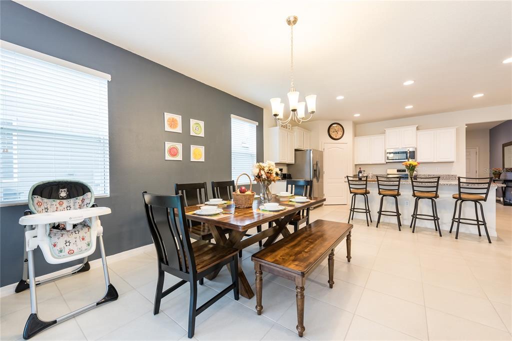 A dining area with a wooden table, bench, chairs, and an adjacent kitchen with bar seating — 5231 WILDWOOD WAY, DAVENPORT, FL