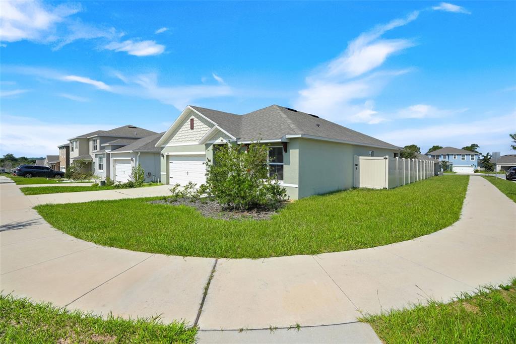 A light green single-story house with a two-car garage sits on a corner lot — 1297 TAGLIAMENTO LANE, HAINES CITY, FL