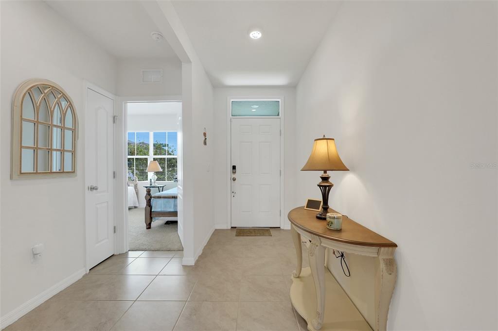 An entryway features a tiled floor, a console table with a lamp, and a doorway — 1297 TAGLIAMENTO LANE, HAINES CITY, FL
