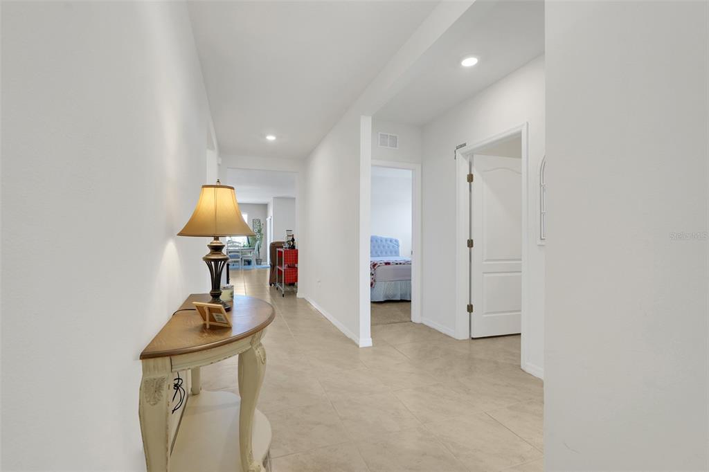 A hallway with tile flooring leads to a bedroom and an open living area — 1297 TAGLIAMENTO LANE, HAINES CITY, FL
