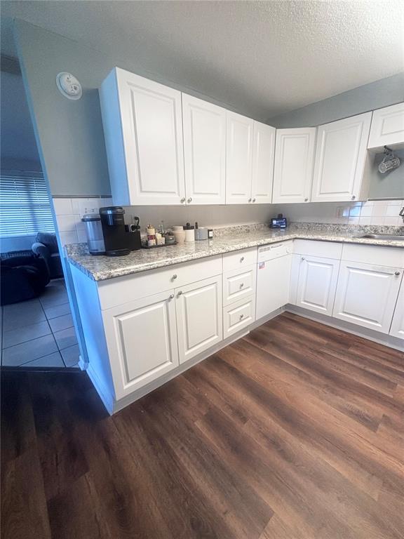 A kitchen features white cabinets, granite countertops, and wood-look flooring — 4824 8TH STREET, ZEPHYRHILLS, FL
