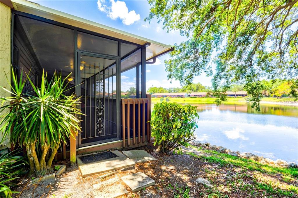 A screened-in porch overlooks a lake with trees and distant buildings in the background — 4612 PARK LAKE TERRACE N, BRADENTON, FL