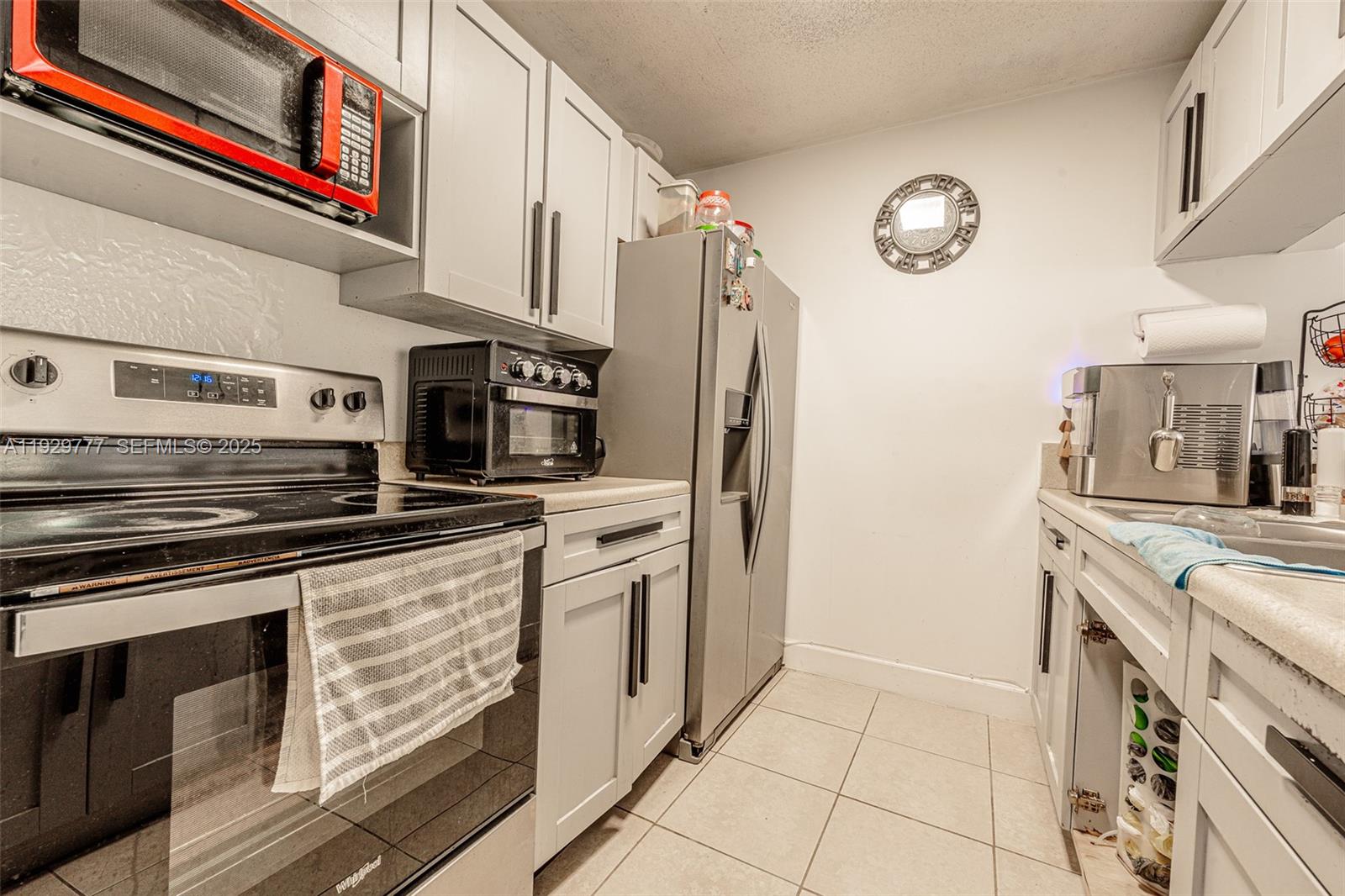 A kitchen features light gray cabinets, stainless steel appliances, and a tiled floor — 8006 SW 149th Ave # D109, Miami FL 33193, MIAMI, FL