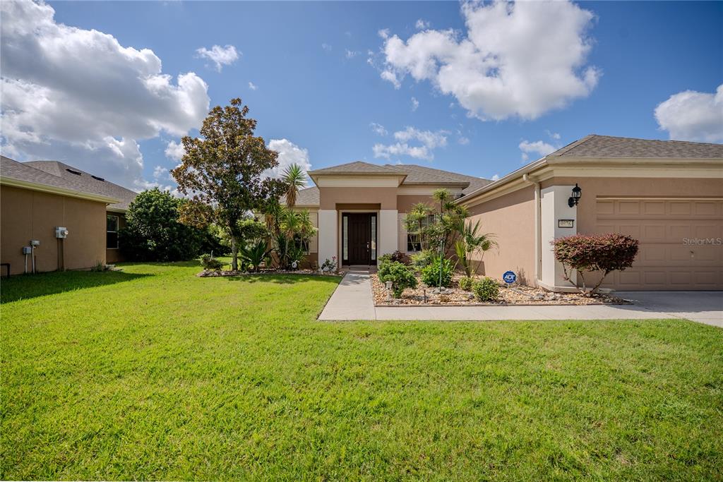 A single-story suburban house with a tan stucco exterior, a garage, and a front walkway — 9876 SW 69TH LANE, OCALA, FL