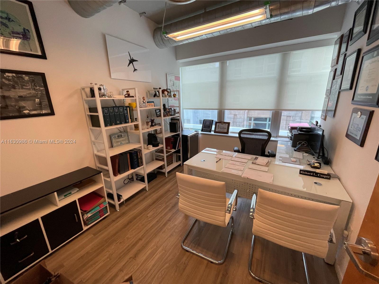 A home office features a white desk, two white chairs, shelving units, and wood-look flooring — 14 NE 1st Ave # 300A, Miami FL 33132, MIAMI, FL