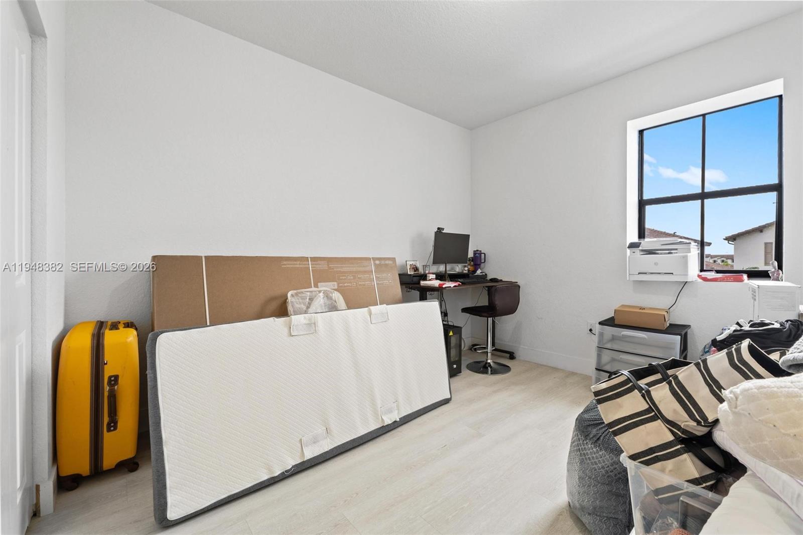 A room with light wood-look flooring, a desk, a window, and various stored items — 12927 SW 229th Ter, Miami FL 33170, MIAMI, FL
