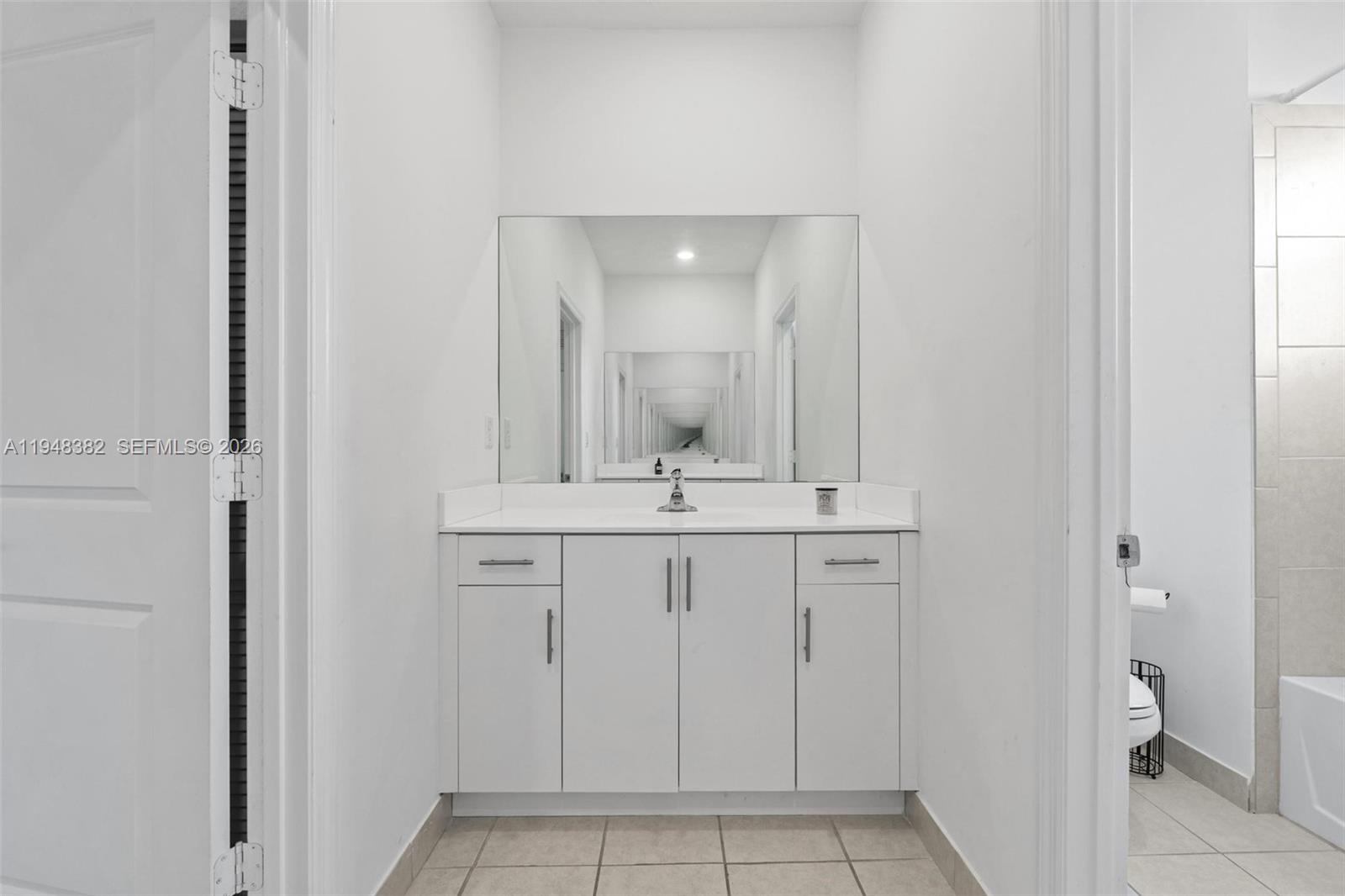 A bathroom features a white vanity with a mirror and tiled flooring — 12927 SW 229th Ter, Miami FL 33170, MIAMI, FL
