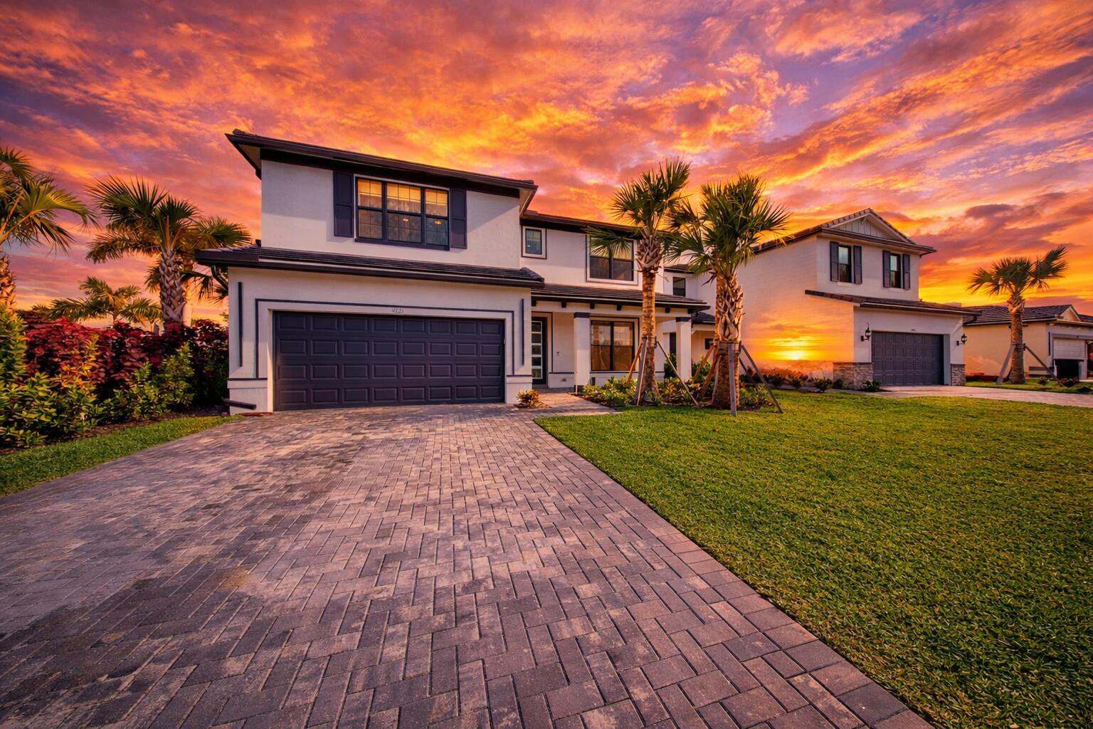 A two-story house with a paved driveway, palm trees, and a vibrant sunset sky — 9721 Chora Tunel Way, Lake Worth FL 33467, LAKE WORTH, FL