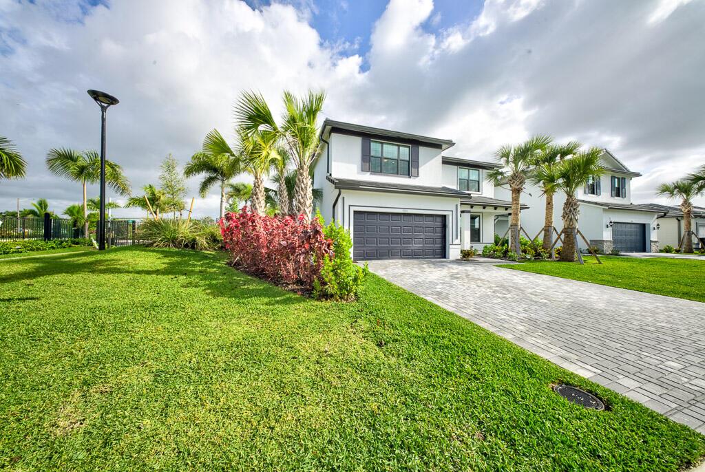 A two-story white house with a gray garage and a paved driveway under a cloudy sky — 9721 Chora Tunel Way, Lake Worth FL 33467, LAKE WORTH, FL