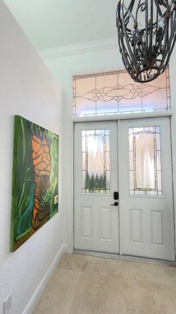 A foyer features a double front door with glass inserts, tile flooring, and a chandelier — 706 Via Genova, Deerfield Beach FL 33442, DEERFIELD BEACH, FL