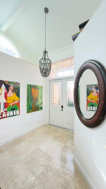 A bright foyer features a high ceiling, a hanging lantern, tile floors, and wall art — 706 Via Genova, Deerfield Beach FL 33442, DEERFIELD BEACH, FL