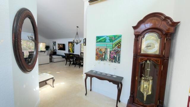 An entryway features a grandfather clock, a console table, and a mirror leading into a living area — 706 Via Genova, Deerfield Beach FL 33442, DEERFIELD BEACH, FL
