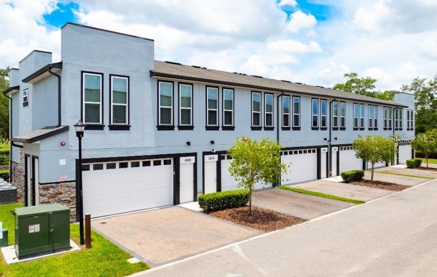 A multi-unit residential building features light blue stucco siding, dark window frames, and attached garages — 2109 BROOME STREET, KISSIMMEE, FL