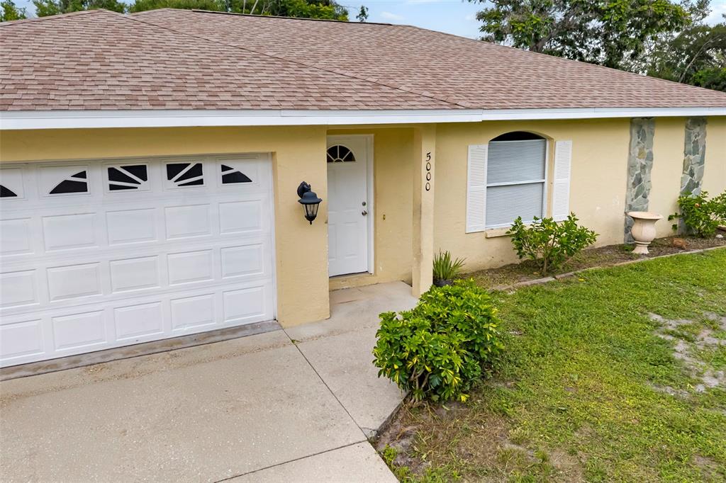 A single-story house with a yellow exterior, a white garage door, and a shingled roof — 5000 MINK ROAD, SARASOTA, FL