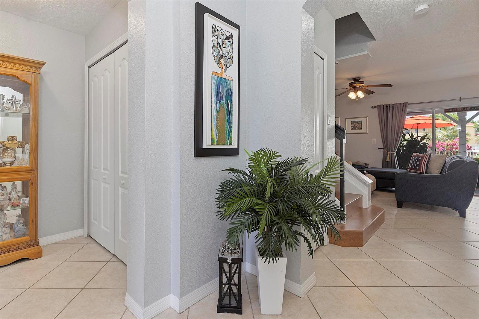 A foyer with tile flooring, a wooden display cabinet, a potted plant, and wall art — 12955 SW 28TH Court, Miramar FL 33027, MIRAMAR, FL