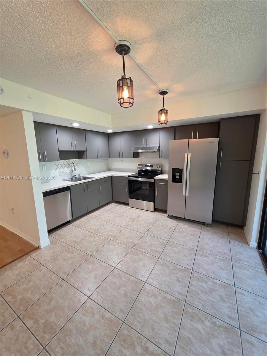 A kitchen features gray cabinetry, stainless steel appliances, white countertops, and light-colored tile flooring — 8065 SW 107th Ave # 214, Miami FL 33173, MIAMI, FL