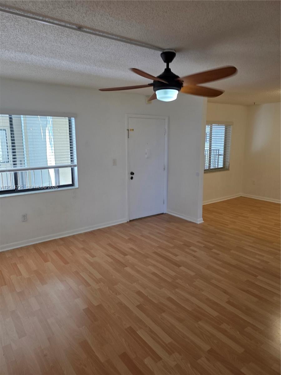 An empty room features light wood-look flooring, white walls, a ceiling fan, and two windows — 8065 SW 107th Ave # 214, Miami FL 33173, MIAMI, FL