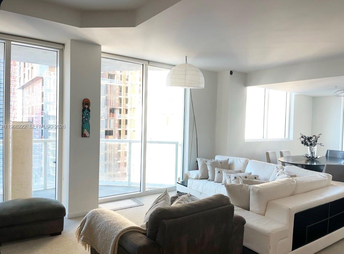 A living room with a white sectional sofa, a floor lamp, and floor-to-ceiling windows — 253 NE 2nd St # 3903, Miami FL 33132, MIAMI, FL