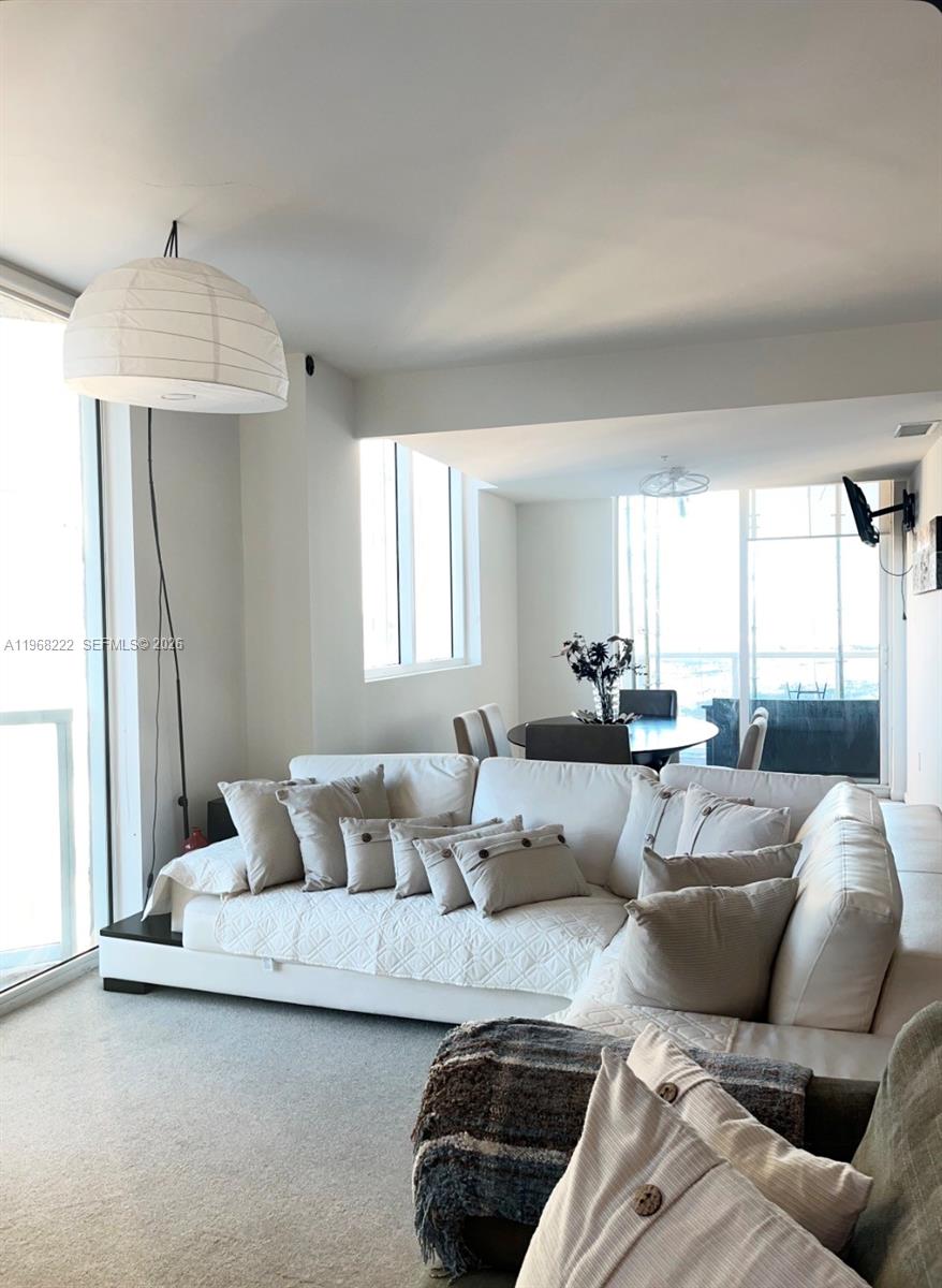 A living room features a large white sectional sofa, a paper pendant lamp, and dining area — 253 NE 2nd St # 3903, Miami FL 33132, MIAMI, FL