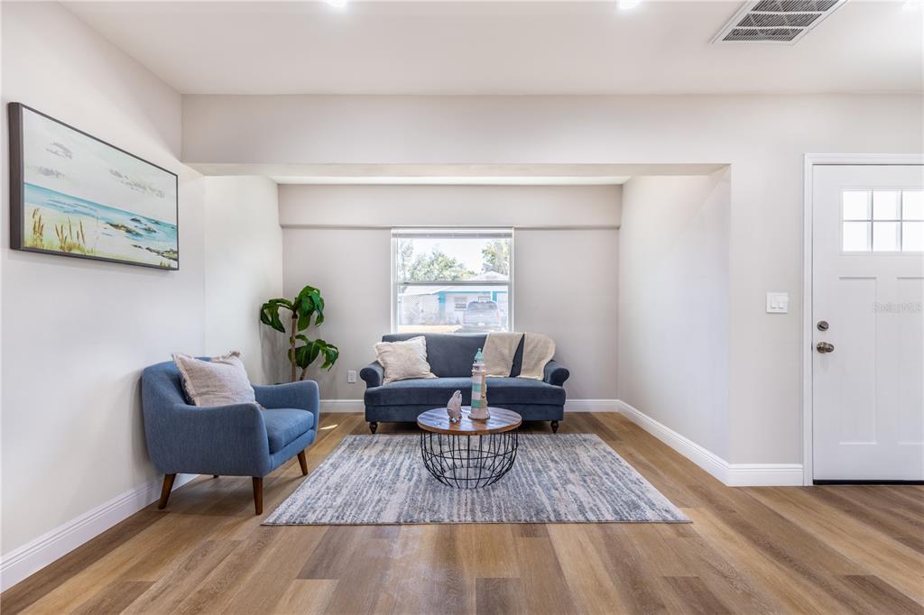 A living room features blue furniture, a round wire coffee table, and wood-look flooring — 307 LEGION PLACE, PORT ORANGE, FL
