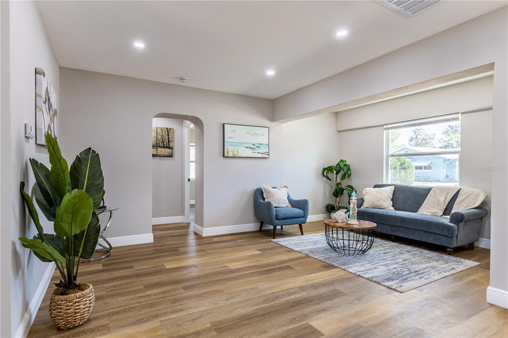 A living room features light gray walls, wood-look flooring, a blue sofa, and an armchair — 307 LEGION PLACE, PORT ORANGE, FL