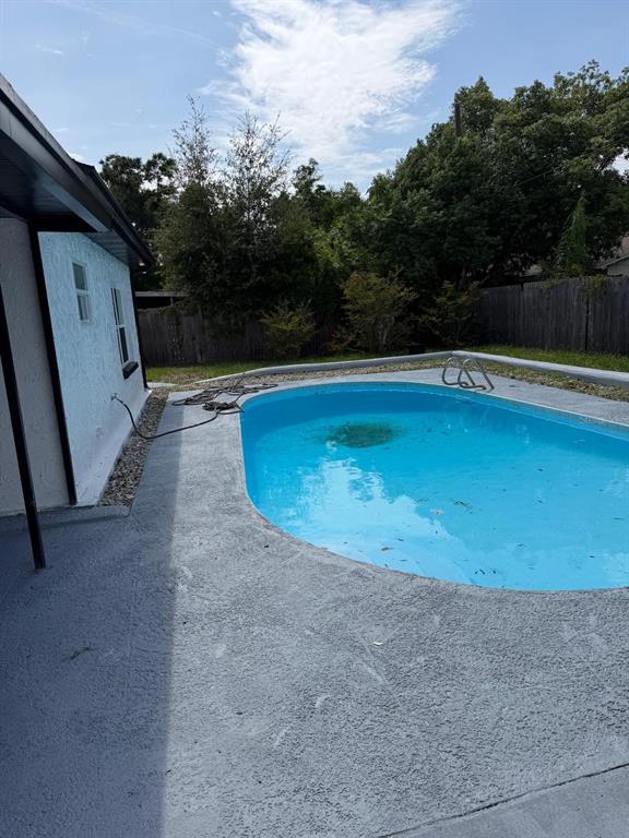 A backyard features a blue swimming pool with a concrete deck next to a house — 4416 COBIA DRIVE, TAMPA, FL