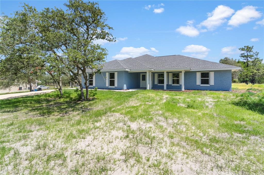 A blue, single-story house with a gray shingled roof sits on a grassy lot — 11751 NE 108TH STREET, ARCHER, FL