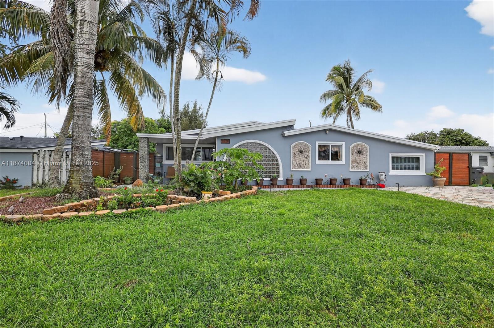 A backyard features a rectangular swimming pool, a patio, and a red wooden fence — 7120 Wilson St, Hollywood FL 33024, HOLLYWOOD, FL