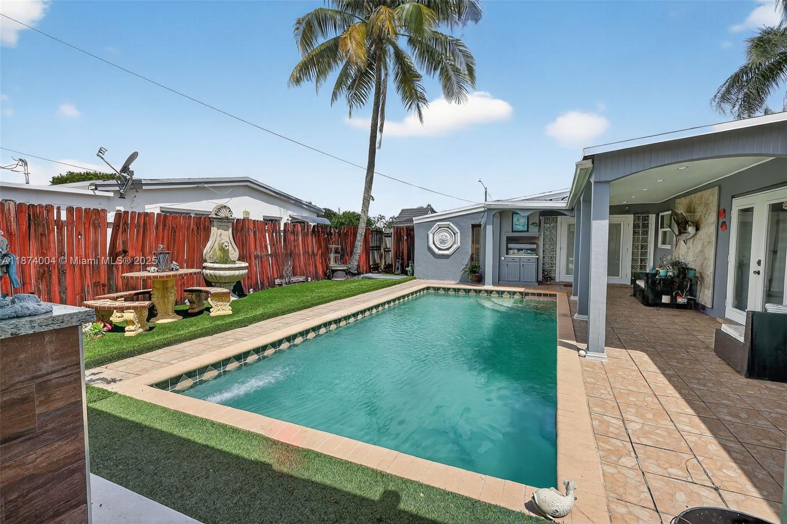 A covered front porch features a white door, glass block accents, and outdoor seating — 7120 Wilson St, Hollywood FL 33024, HOLLYWOOD, FL