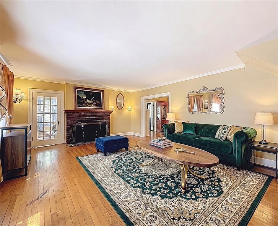 A living room features a brick fireplace, a green velvet sofa, and a patterned area rug — 800 W LAKE ELBERT DRIVE NE, WINTER HAVEN, FL