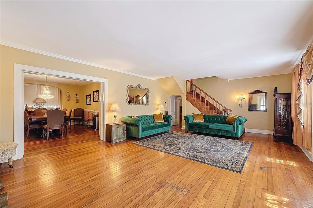 A living room with two green tufted sofas, hardwood floors, and a staircase — 800 W LAKE ELBERT DRIVE NE, WINTER HAVEN, FL