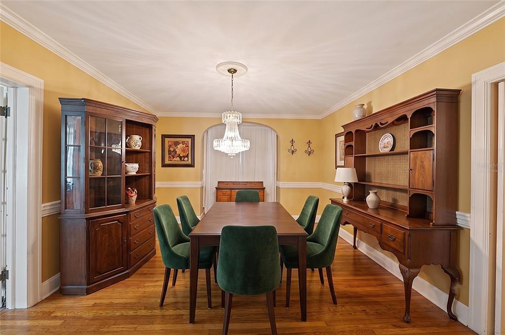 A formal dining room features a wooden table, green velvet chairs, and two large hutch cabinets — 800 W LAKE ELBERT DRIVE NE, WINTER HAVEN, FL