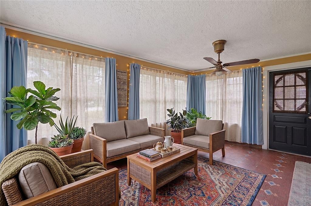 A sunroom features wicker furniture, a patterned area rug, blue curtains, and a ceiling fan — 800 W LAKE ELBERT DRIVE NE, WINTER HAVEN, FL