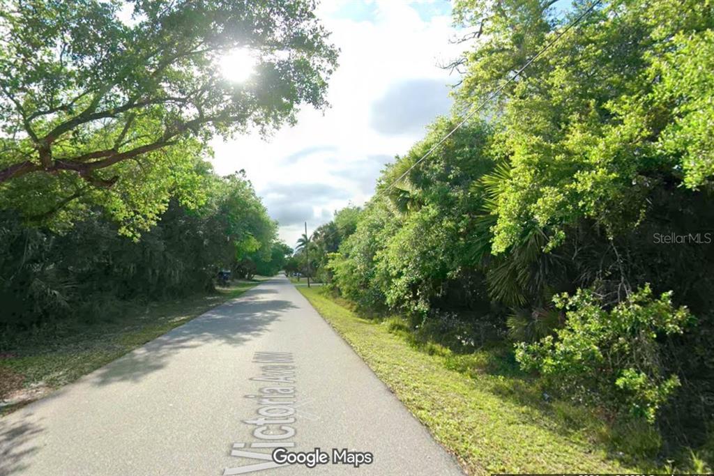 A paved road stretches through a wooded area with dense trees on both sides — 1041 VICTORIA AVENUE, PORT CHARLOTTE, FL