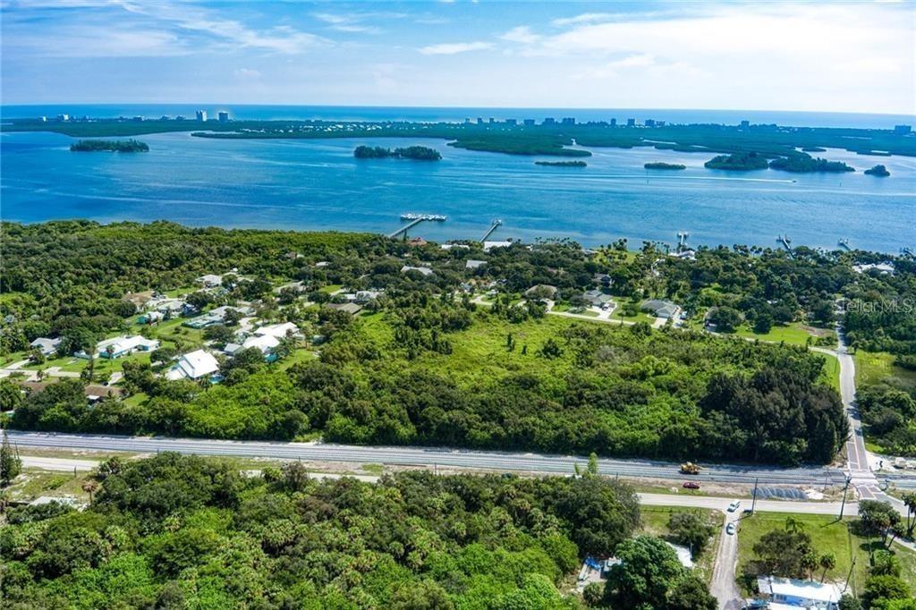 An aerial view shows a large, wooded lot near a bay with distant coastal buildings — 0 MILTON ROAD & RIVER WOODS DRIVE, FORT PIERCE, FL
