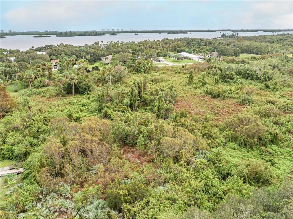 An aerial view shows a dense, wooded lot overlooking a large body of water — 0 MILTON ROAD & RIVER WOODS DRIVE, FORT PIERCE, FL