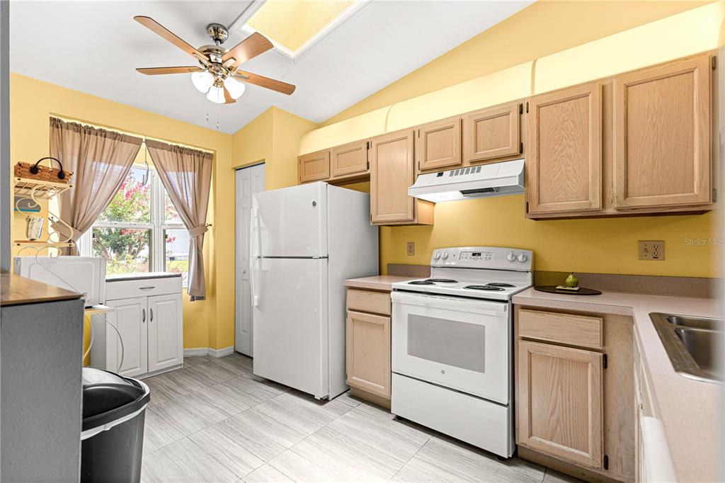 A kitchen with light wood cabinets, white appliances, yellow walls, and a ceiling fan — 10483 SW 85TH COURT, OCALA, FL